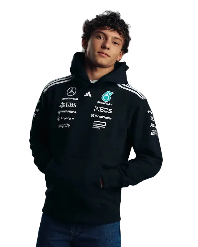 Person wearing a black hoodie with various logos on a gray background