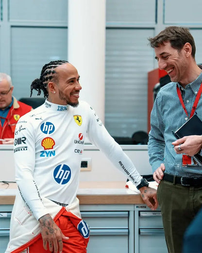 Lewis racing driver in a white suit with sponsor logos.