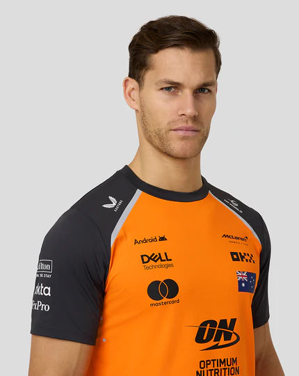 Man wearing an orange and black sports jersey with various sponsor logos on a gray background