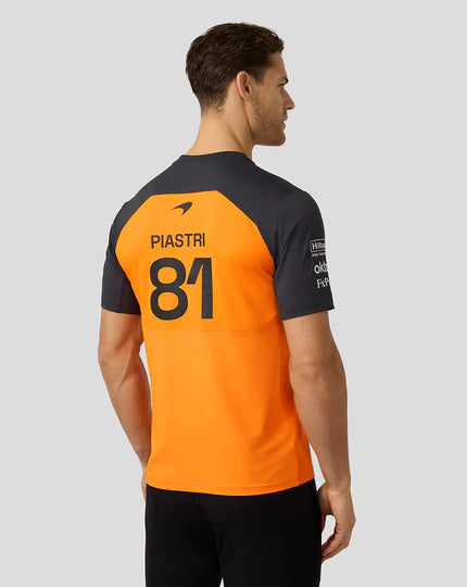 Person wearing a black and orange sports jersey with 'PIASTRI' and number '81' on a gray background