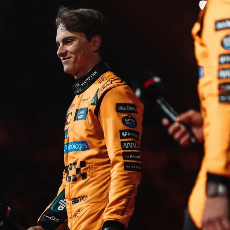 Front-facing shot of Oscar Piastri in the McLaren F1 2025 papaya orange and black racing suit with sponsor logos