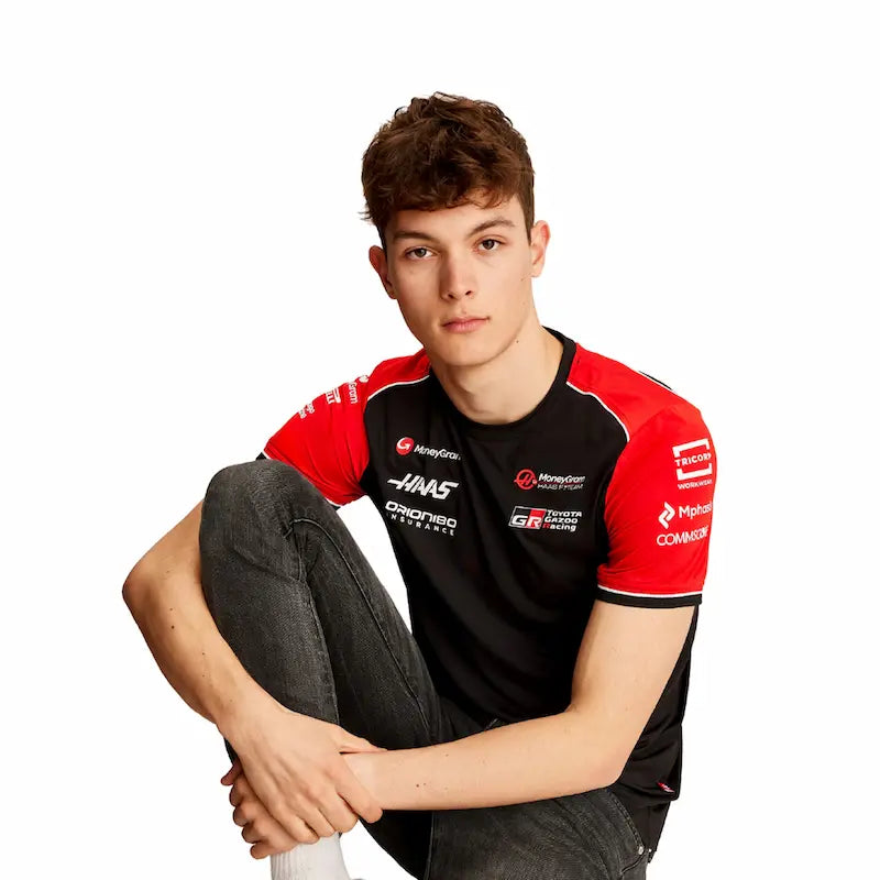 Person wearing a red and black racing shirt with various logos on a white background