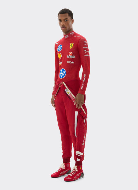 Person wearing a red racing suit with various sponsor logos on a white background